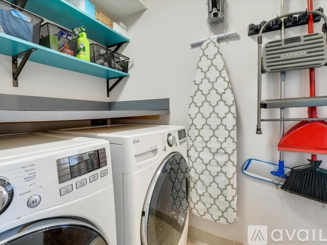 A laundry room with a washer and dryer, a hanging towel, and a shelf with various items.