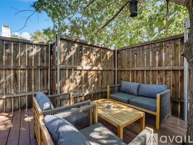 A wooden deck with a grey couch and a wooden coffee table.