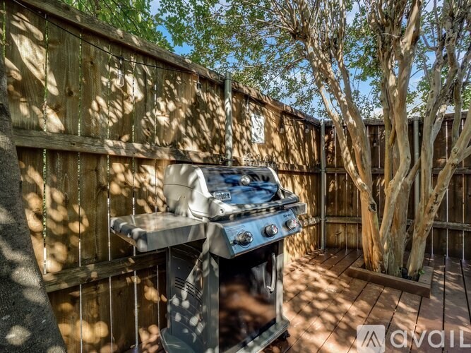 A BBQ grill is in the middle of a wooden deck.