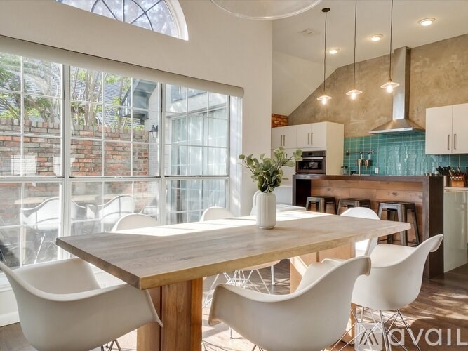 A dining area with a wooden table and white chairs.