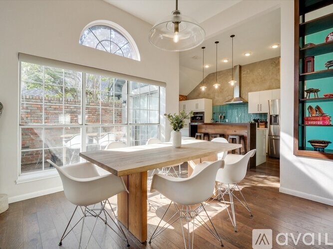 A modern dining room with a wooden table and white chairs.
