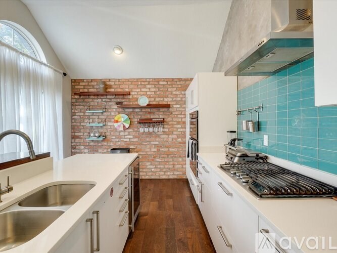 A kitchen with a white countertop and a brick wall.