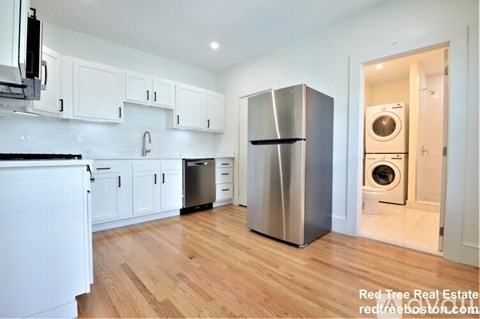 A kitchen with white cabinets and a stainless steel refrigerator.