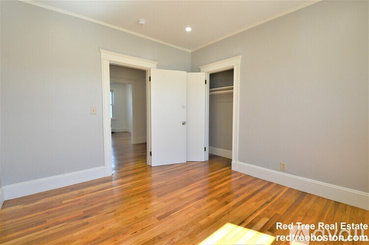 A room with wooden floors and white walls, with two open doors.