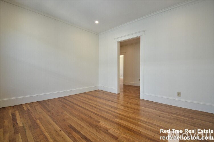 A room with wooden floors and a doorway leading to another room.