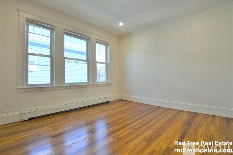 A room with wooden floors and two windows.