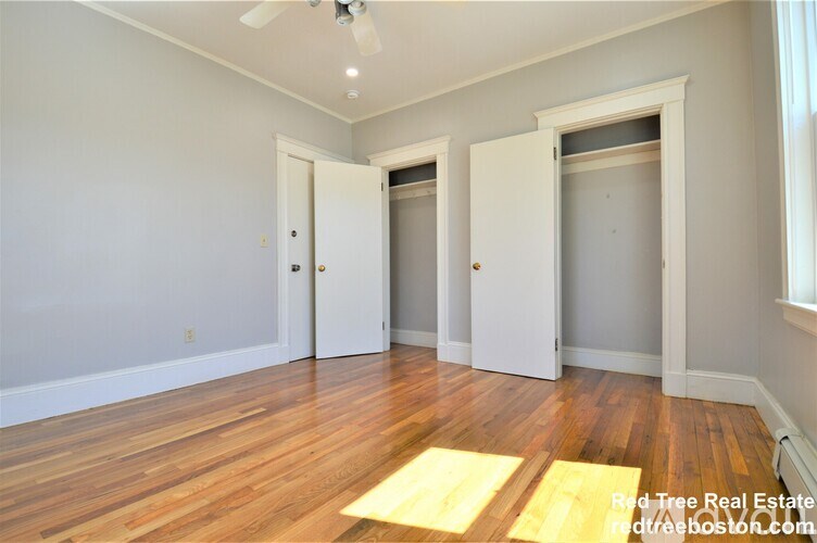A room with wooden floors and white walls with three doors.