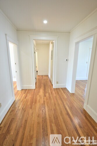 A hallway with wooden floors and white walls.
