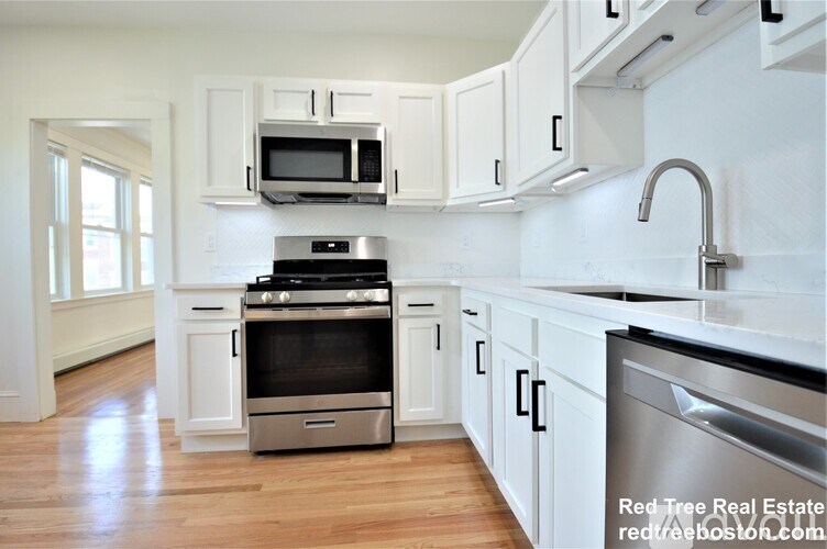 A modern kitchen with white cabinets and stainless steel appliances.