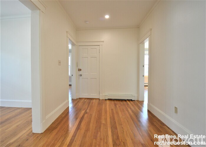 A hallway with wooden floors and white walls.