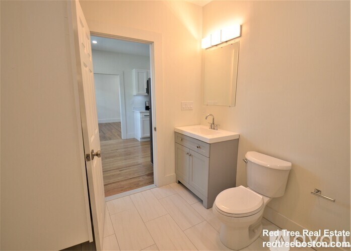 A bathroom with a toilet, sink, and mirror.