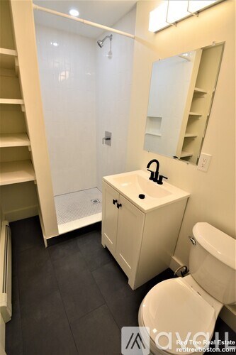 A white bathroom with a sink, toilet and a walk in shower.