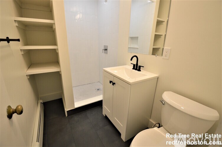 A white bathroom with a toilet, sink, and a mirror.