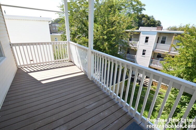 A balcony with a white railing and wooden floor.