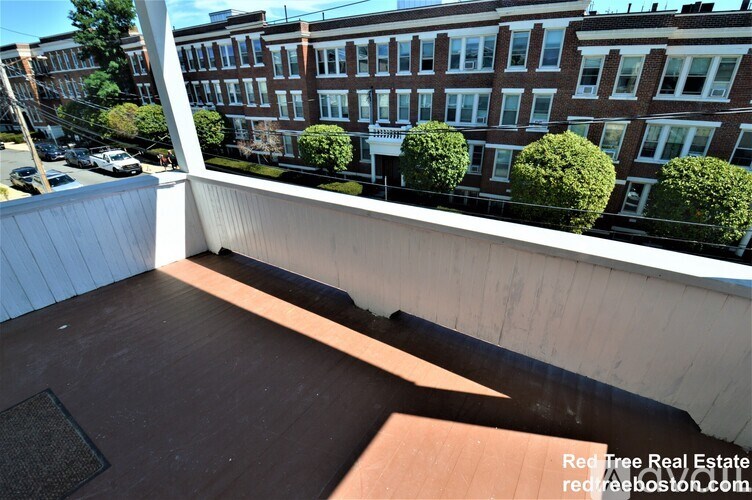 A balcony with a white railing and a brown floor.