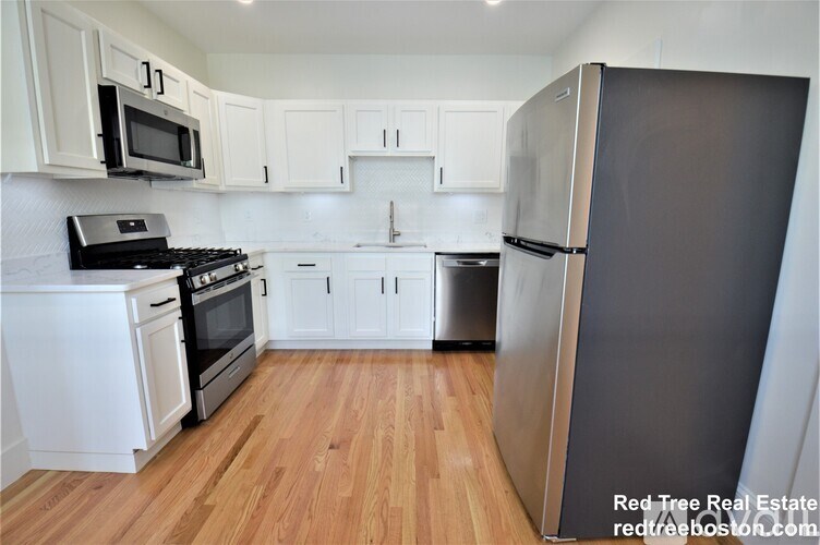 A kitchen with white cabinets and a wooden floor.