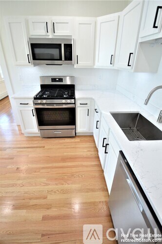 A kitchen with white cabinets and a wooden floor.