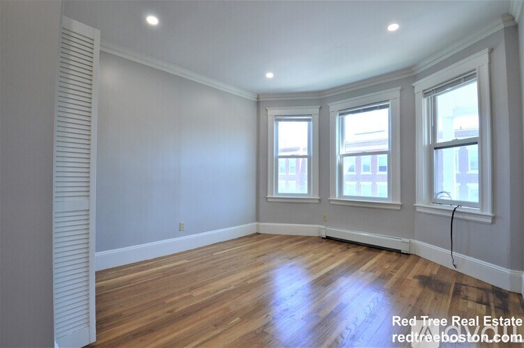 A room with wooden floors and three windows.
