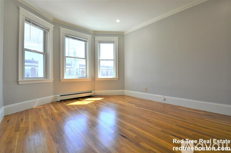 A room with wooden floors and three windows.