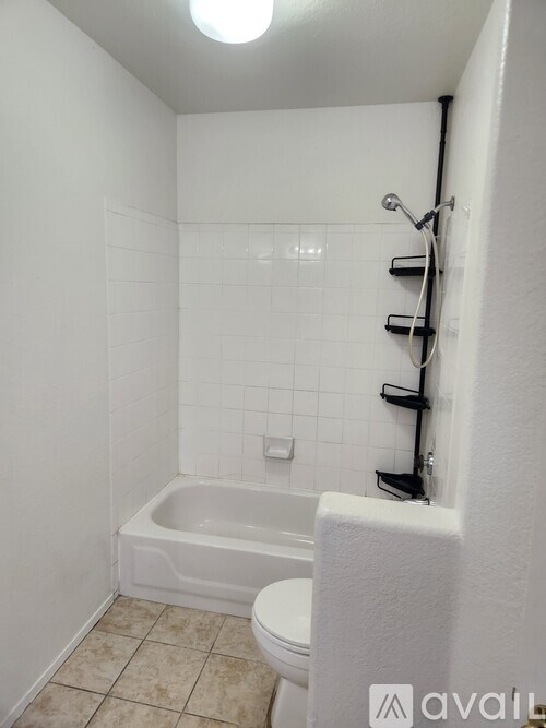 A white bathroom with a toilet, tub, and shelves.