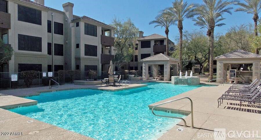 A large swimming pool surrounded by palm trees and lounge chairs.