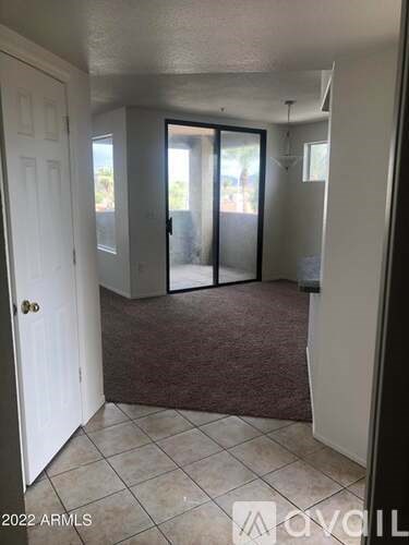 A room with a white door, a brown carpet, and a white wall.