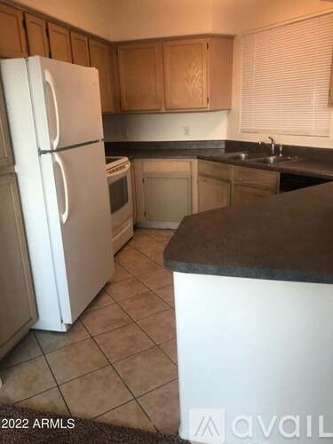 A kitchen with a white refrigerator and brown cabinets.