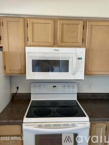 A white microwave oven is on top of a white stove in a kitchen.