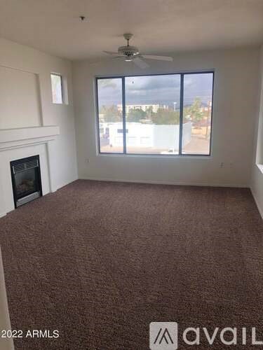 A room with a carpeted floor, a fireplace, and a ceiling fan.