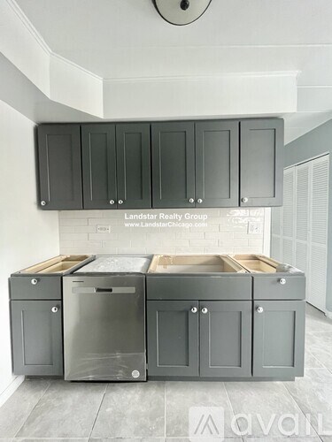 A kitchen with grey cabinets and a white wall.