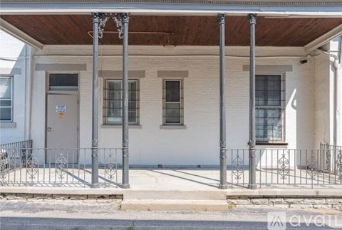A white building with a brown roof and a metal fence in front.
