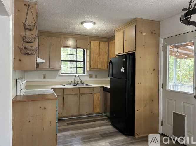 A kitchen with wooden cabinets and a black refrigerator.