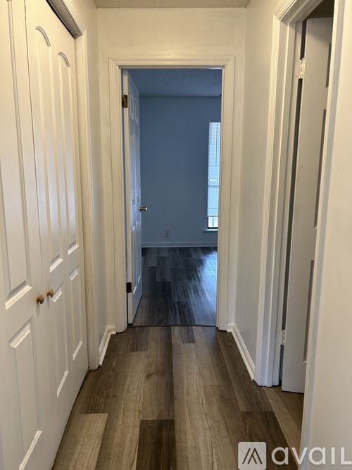 A long hallway with white doors and wood floors.