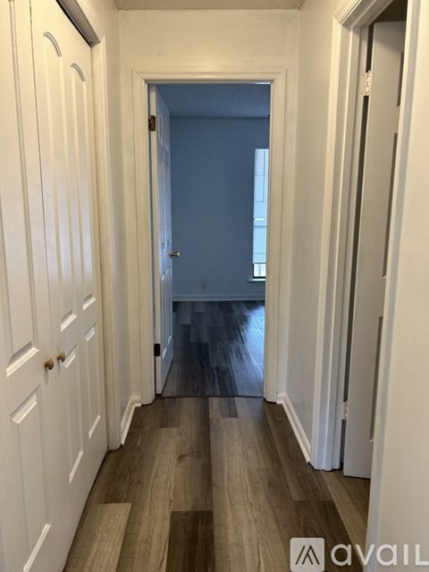 A long hallway with white doors and wood floors.