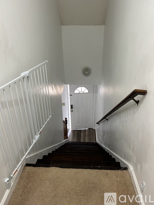 A carpeted staircase with a white railing and a white door at the top.