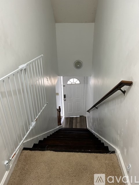 A carpeted staircase with a white railing and a white door at the top.