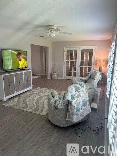 A living room with a television and a chair with a blanket on it.
