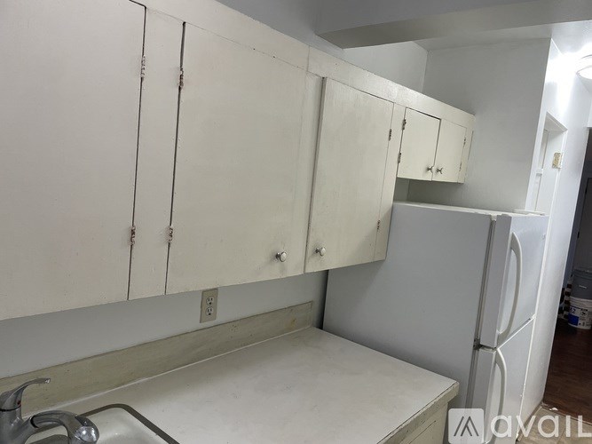 A kitchen with white cabinets and a white fridge.