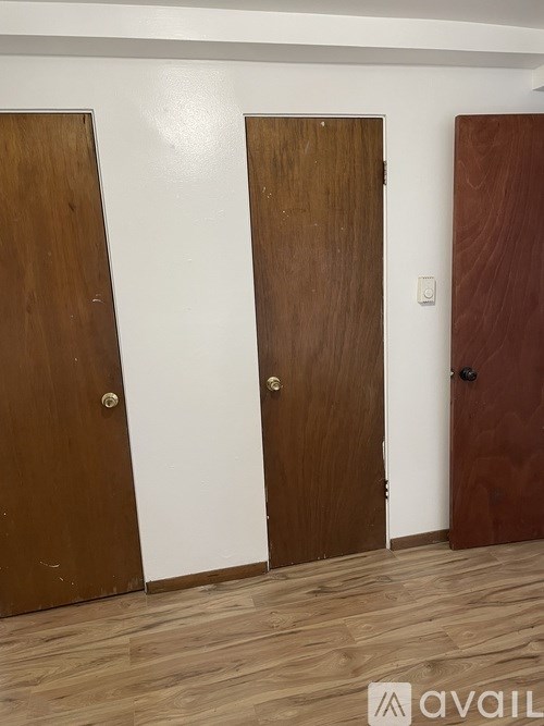 Three brown doors in a white room.