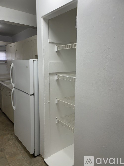 A white refrigerator with empty shelves in a kitchen.