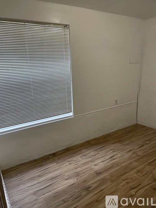 A room with wooden flooring and a window with blinds.