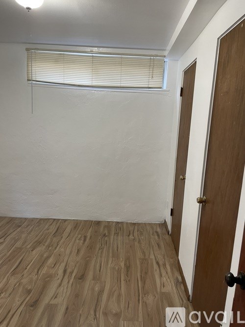 A room with wooden flooring and a brown door.