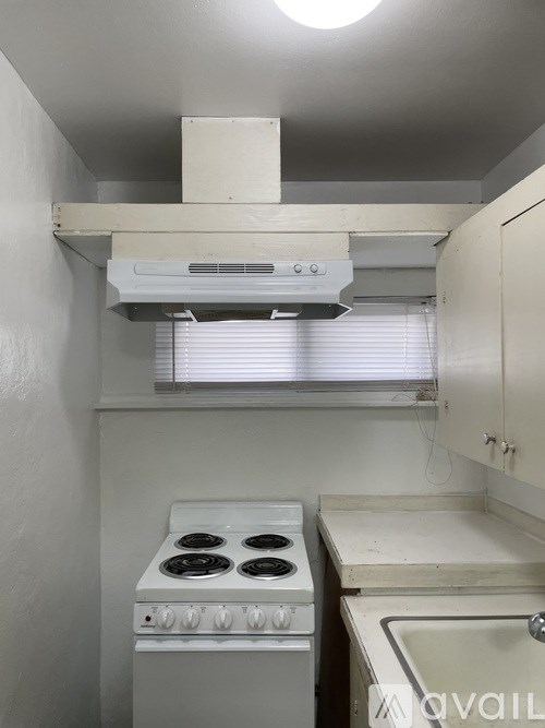 A small kitchen with a stove, sink, and window.