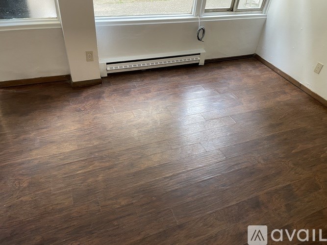 A room with wooden flooring and a window with a white frame.