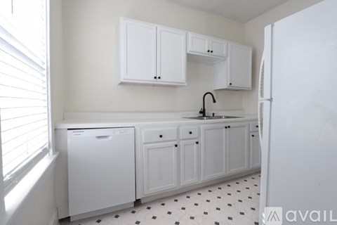 A kitchen with white cabinets and a black and white floor.