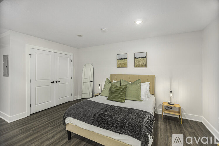 A bedroom with a bed, two pictures on the wall, and a wooden nightstand.