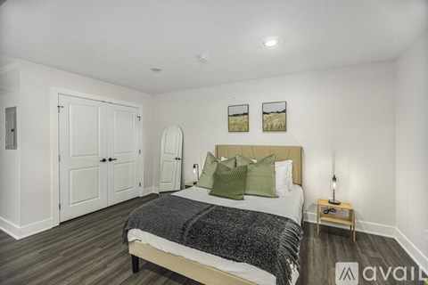 A bedroom with a bed, two pictures on the wall, and a wooden nightstand.