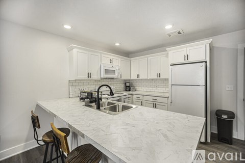 A kitchen with white cabinets and a marble countertop.