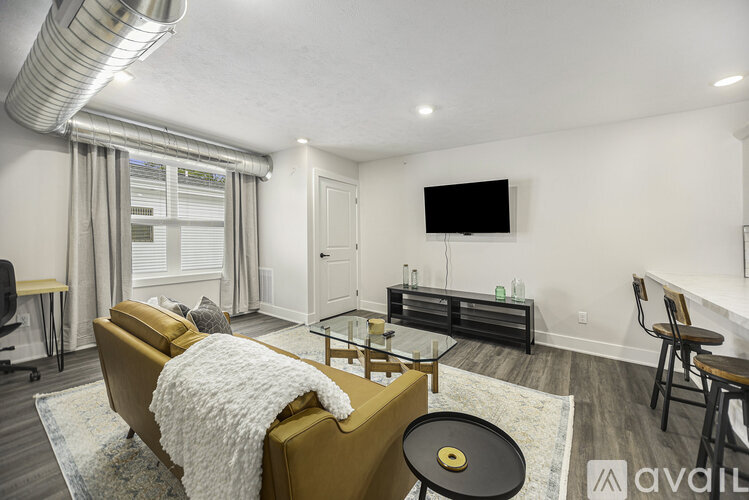 A living room with a yellow couch and a black coffee table.