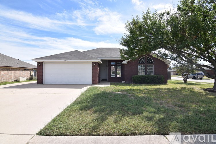 A house with a garage and a tree in front.